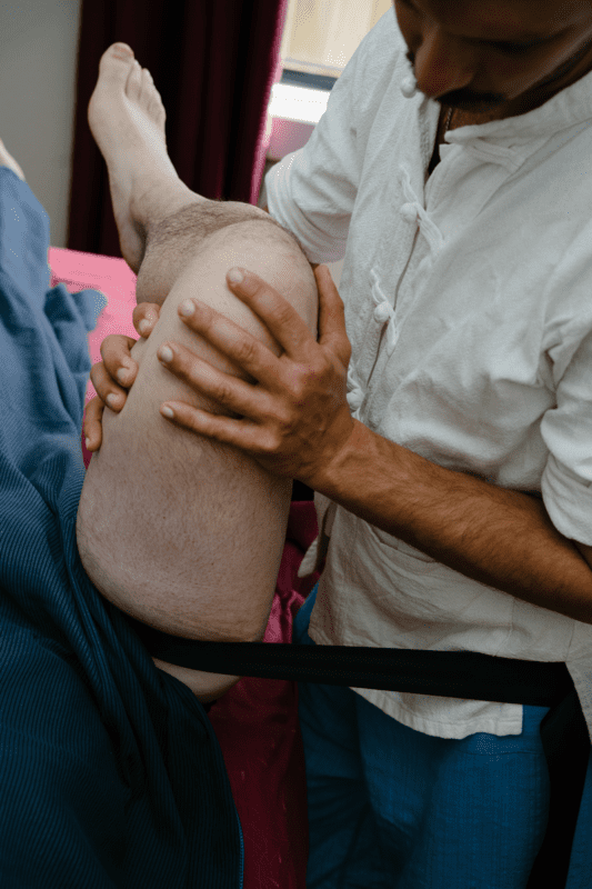 Giovanni using a belt to deliver a mobilisation on hip for hip impingement