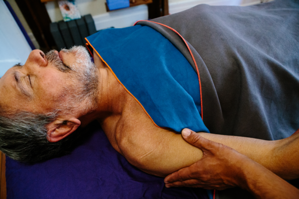 Giovanni with his hand delivering Lymphatic Drainage Massage on a patient shoulder