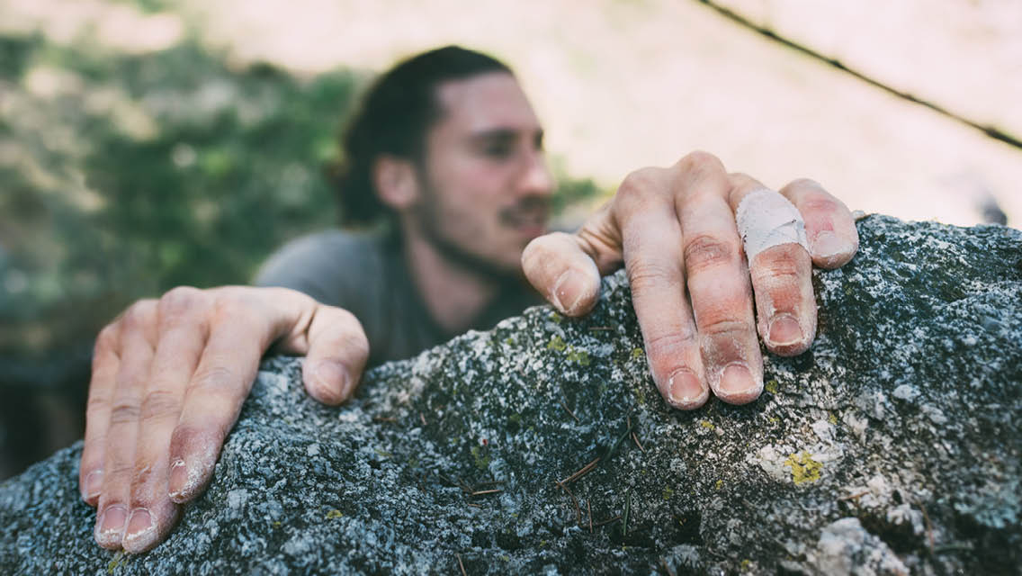 Someone relying on a their Grip Strength to hold on to a rock